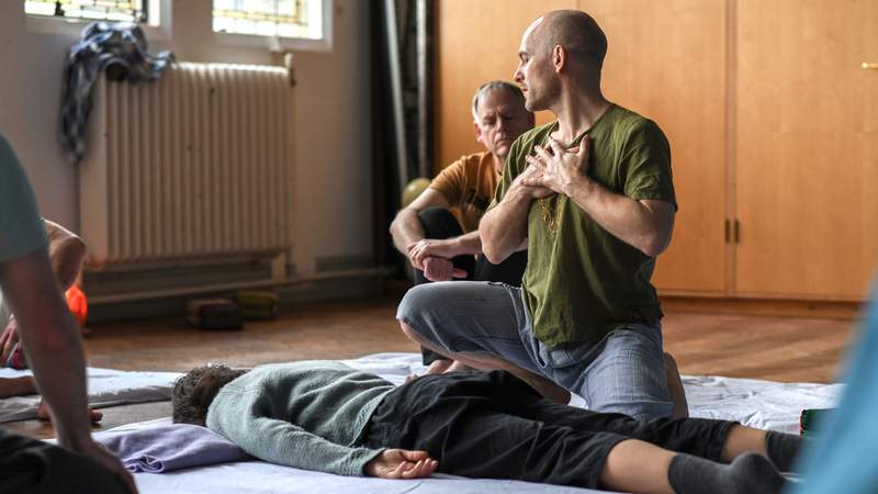 Justin explaining a Thai massage technique to a student in a course.